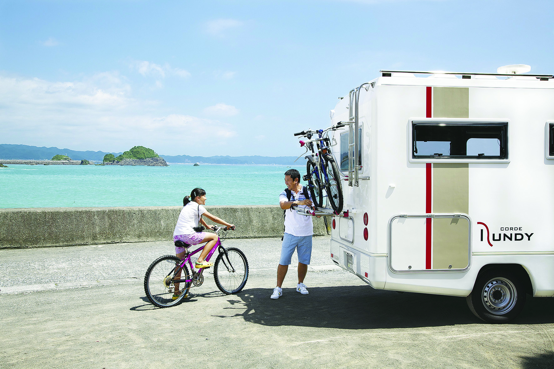 Présentation d'un équipement extérieur indispensable en camping-car : le porte-vélo. Avec des camping-caristes en train de ranger leurs vélos sur le porte-vélo du camping-car.